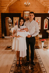 Letychiv, Ukraine - 10.15.2020: rite of sacrament of epiphany baby in church. Newborn baby boy in the arms of godparents in church.