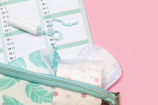 Toallitas higi&eacute;nicas femeninas, tampones menstruales junto a un calendario sobre un fondo rosa. Vista superior. Copy space