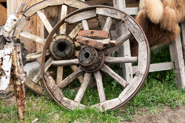 an old wooden cart wheel stands by the fence