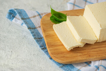 tofu, paneer, soy cheese, curd cheese, brynza, feta, Adyghe cheese on a wooden cutting Board on a light background