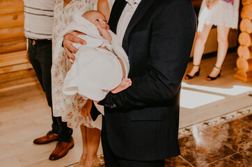 baby hand in arms of godfather. rite of sacrament of epiphany in church