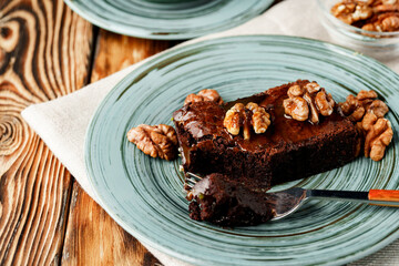 Piece of chocolate cake with nuts on green plate