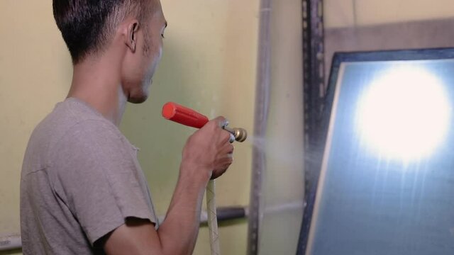 Man preparing silkscreen by hand for used to work printing t-shirts