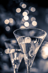 GTwo glasses of champagne against a beautiful blurred christmas decor with star and bokeh light. black and white photographylasses of champagne against a beautiful blurred christmas decor