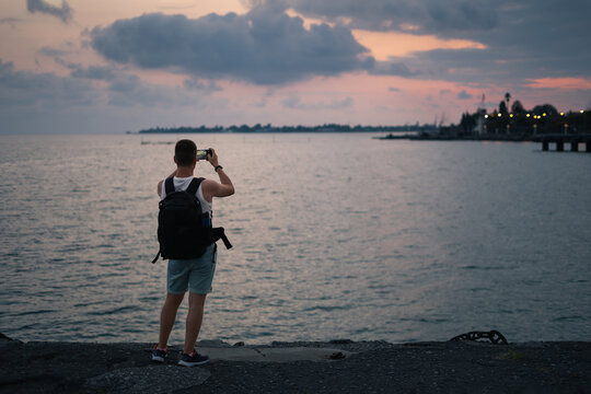 man photographs the sea and sunset
