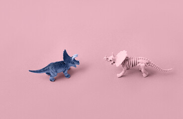 Toy models of dinosaur skeletons on a pink background.