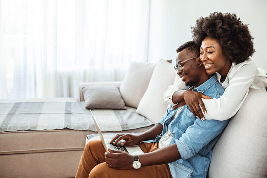Happy African American couple using laptop, receive good news online, email, positive decision from bank, smiling wife and husband looking at screen together, mortgage or loan approve paper letter