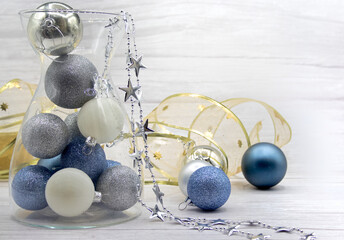 Christmas decoration of a vase with silver, blue, white balls and a garland of stars that fall from the vase, plus balls on the table and a golden garland at the bottom.