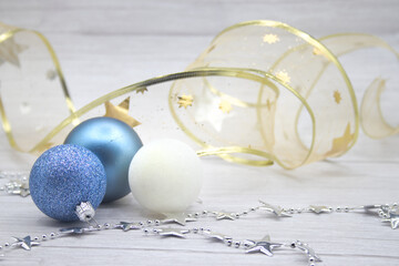 Blue or white Christmas balls with a garland of stars and a golden garland in the background,