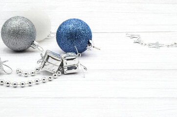 Blue, gray and white Christmas balls on a clear board and a silver garland.