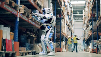 Warehouse robot scanning barcodes on cardboard boxes with two workers in the background - Powered by Adobe