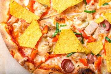 The part of delicious mexican pizza with cheese mozzarella , tomatoes, sausages, bacon, chicken and green onion. Top, close up view.