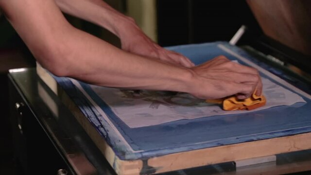 Man preparing silkscreen by hand for used to work printing t-shirts