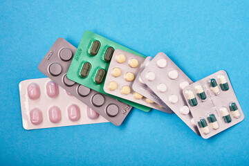 pile of pills in blister packs on blue background