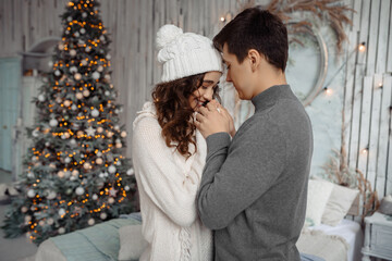 Happy young lovely couple enjoys each other on New Year's Eve in a cozy home environment. New Year's love story.