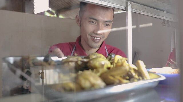 the man took the fried chicken on the iron tray. pecel lele lalapan traditional indonesia food