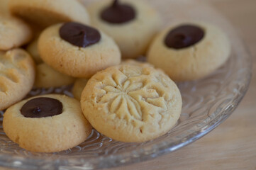 Light brown beige baked peanut cookies filled with dark chocolate, one by one on the plate, tasty Christmas sweets ready to eat