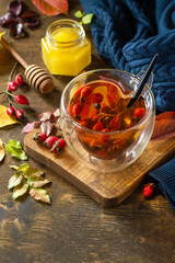 Healthy winter vitamin drink. Hot rosehip tea with honey and dried fruits on a wooden table top. Copy space.