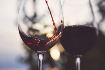 Pouring red wine into a glass at dusk