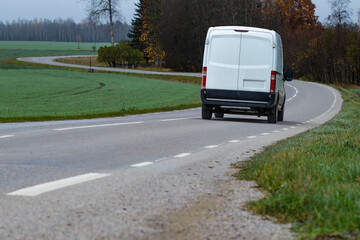 Fototapeta na wymiar A fictional cargo delivery van driving on a curvy countryside road 