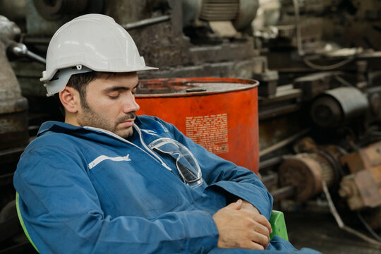 Young engineer, labor or worker man with white halmet  take a nap because so tired after hard work. Sleeping during work, sleep at workplace, Over time employee. Copy Space.