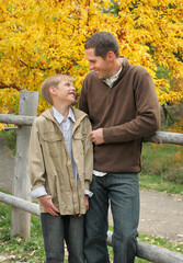 handsome father and son standing together outdoors in fall