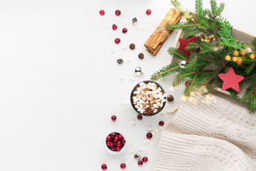 Cup of hot chocolate drink, Christmas festive decorations and cranberries on white wooden background.