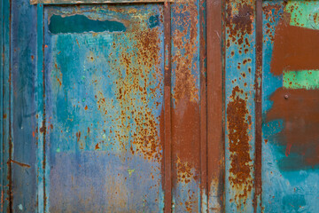 Old flaking paint on rusty door, rust, blue, green, orange, teal, turquoise in graphic patterns, frames and lines 