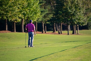 A man golfer finished hitting a hard and difficult golf shot on a hard and difficult luxury country club golf course. 