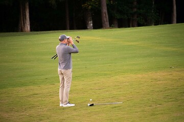 A man golfer scoping and studying and calculating his next shot on the fairway to the golf green on a hard and difficult luxury country club golf course. 