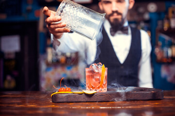 Portrait of barman is pouring a drink at bar