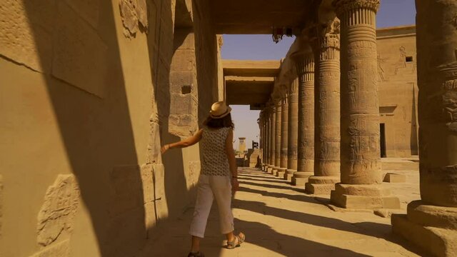 A young woman visiting the beautiful Temple of Philae, a Greco-Roman construction seen from the Nile River, a temple dedicated to Isis, goddess of love. Aswan. Egyptian