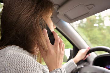 The woman answers the phone while driving, close up