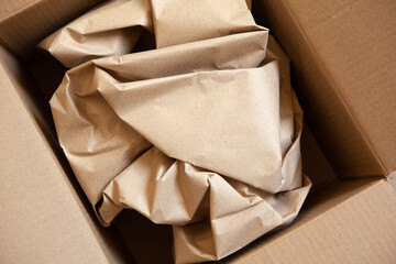 Crumpled wrapping craft brown paper in open after delivery paperboard box. Horizontal. Delivery, ecology, plastic free, resource overrun concept. Flat lay, top view, close-up.