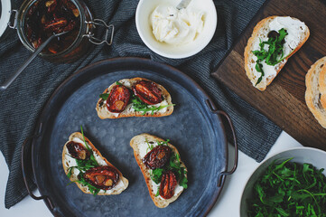 italian traditional bruschetta - bread toast with sun dried tomatoes, cream cheese, olive oil and arugula.