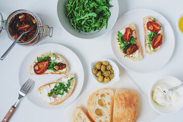 italian traditional bruschetta - bread toast with sun dried tomatoes, cream cheese, olive oil and arugula.