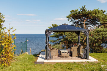 Lounge area for rest and parties with chairs and table in private residence on the coast of Baltic sea. Wooden style outdoor furniture table and chairs for meditation watching the sea and sunset.
