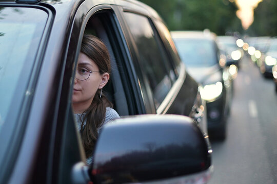 A young woman sits in a car during rush hour