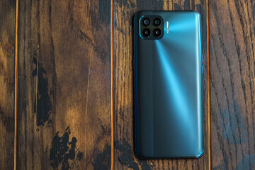 Mobile phone with holographic design with four cameras on a wooden background