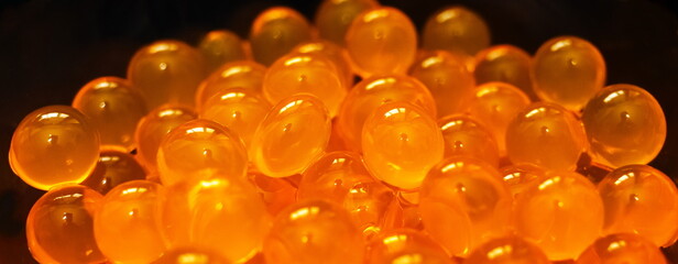 Orange gel round hydroponics balls in glass clear Cup on black background