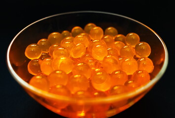 Orange gel round hydroponics balls in glass clear Cup on black background