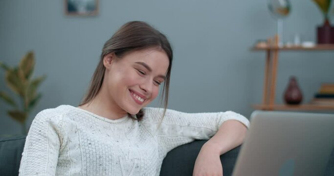 Millennial female person having video conversation while using laptop. Beautiful woman smiling and telling with sign language So much happy for you while sitting at home. Hearing loss.