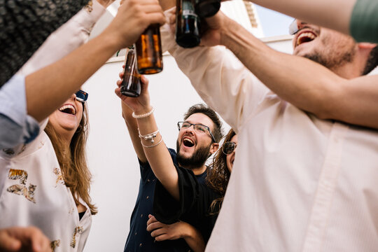 portrait of a group of friends toasting and celebrating. Everyone smiles and holds a beer each