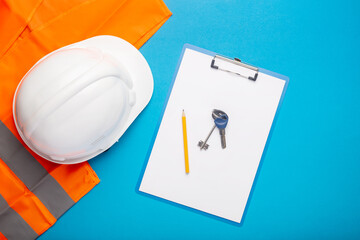 Construction hat, signal vest, apartment keys and clipboard on a light blue background. Concept for construction, renovation work, new building, purchase of an apartment. Banner. Flat lay, top view