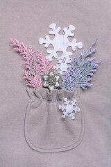 Happy New Year composition in the pocket of a gray fleece jacket. Christmas or winter still life made of snowflakes and cypress branches on gray background. Flat lay, top view.