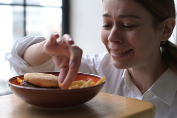 A plate of fast food seduces a young woman who cannot resist and takes fries