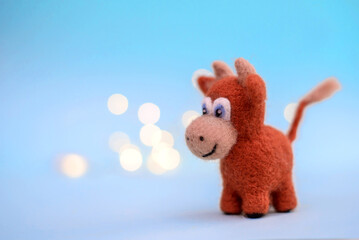 Felt toy bull on a blue background with bokeh