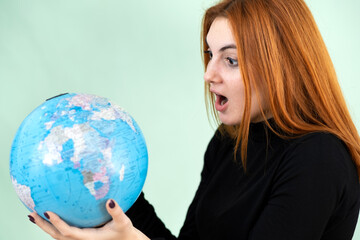 Portrait of a sad worried young woman holding geographic globe of the world in her hands. Travel destination and planet protection concept.