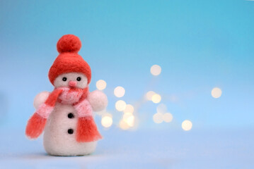 Toy wool snowman on a blue background with bokeh