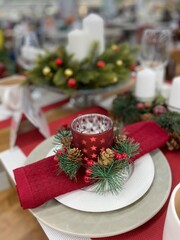 Composition with a red Christmas candle holder standing on a white plate on a new year's table.